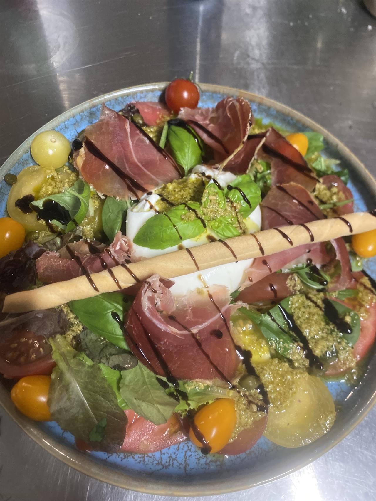 Salade burrata, jambon cru, pesto et tomates anciennes
