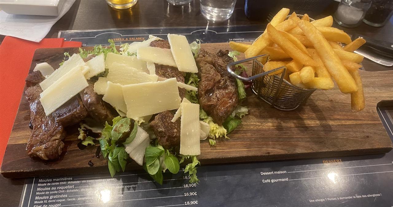 Tagliata de bœuf aux copeaux de parmesan servie sur planche avec un panier de frites